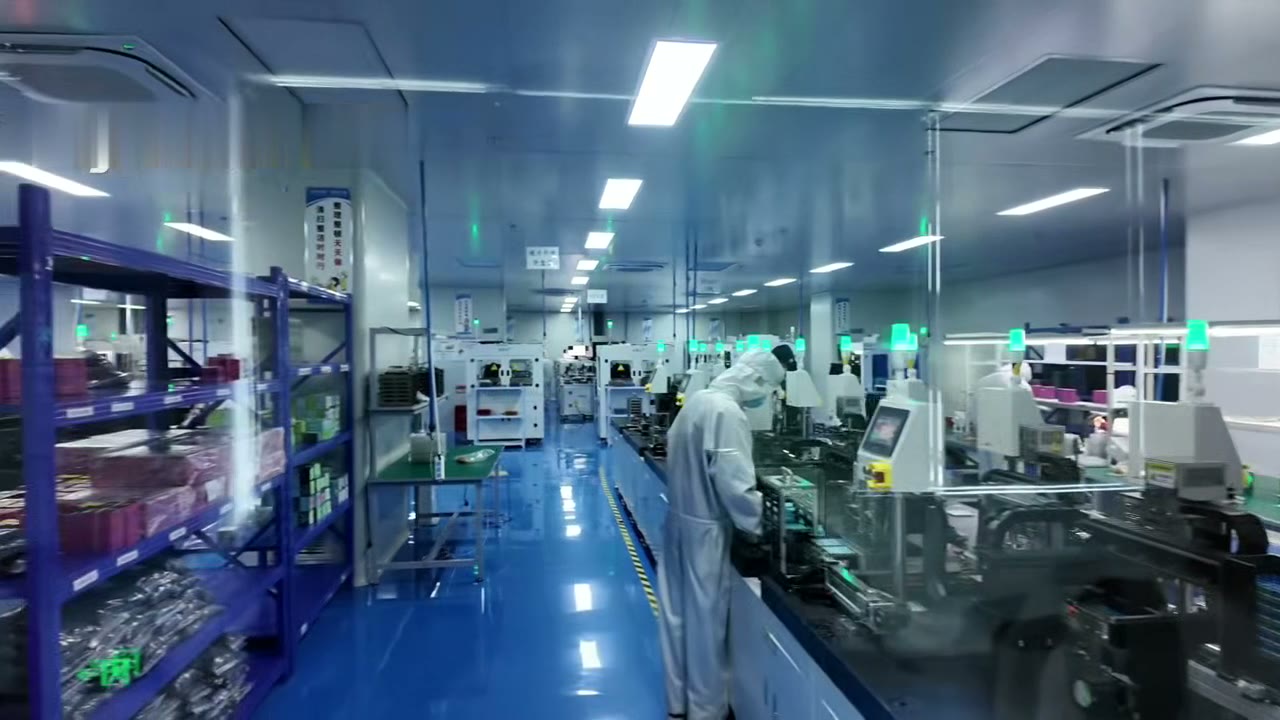 Technician in a cleanroom gown working at a Lensmind alignment station